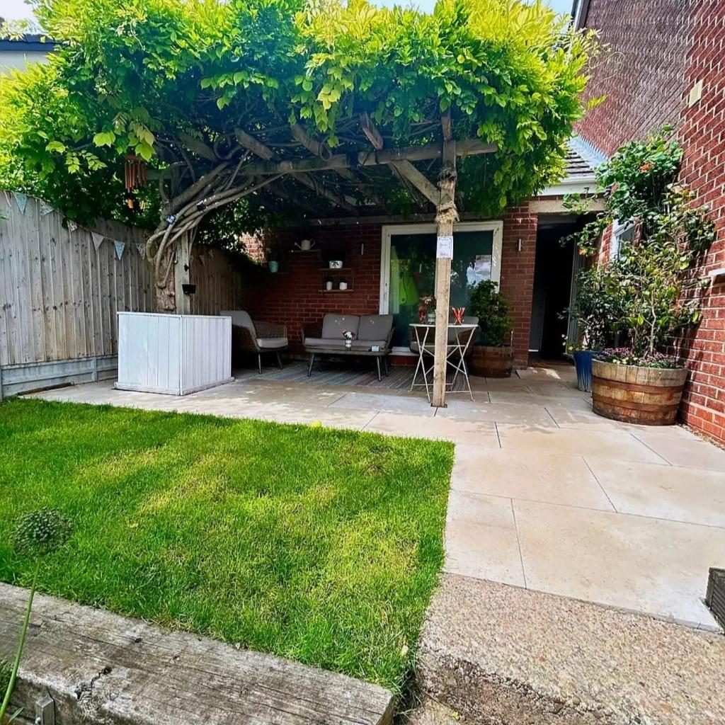 A finished garden terrace with paving, a pergola and lawn